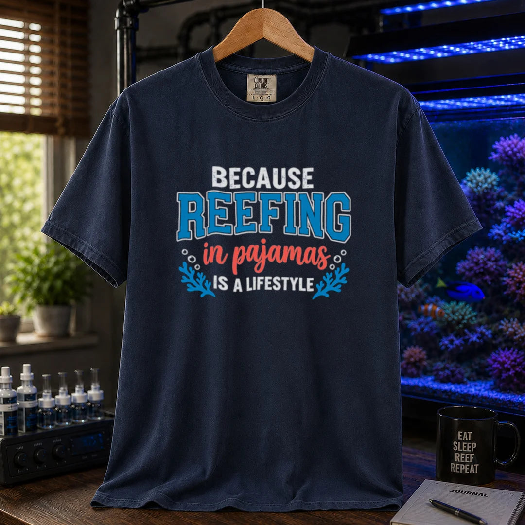 Saltwater aquarium graphic t-shirt featuring distressed typography reading Because Reefing In Pajamas Is A Lifestyle with blue coral and bubble illustrations on a navy shirt