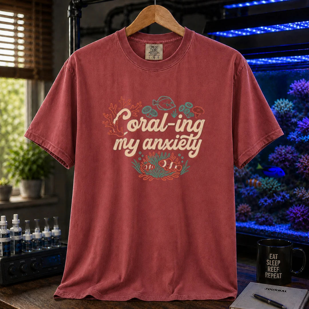 Saltwater aquarium graphic t-shirt featuring handwritten typography reading Coral-ing My Anxiety with colorful coral and fish illustrations on a maroon, red shirt