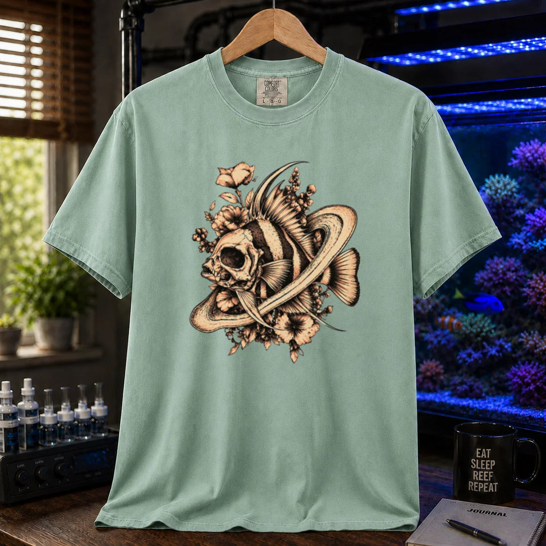 Saltwater aquarium graphic t-shirt featuring an intricate sepia line-art illustration of a fish skull surrounded by flowers and swirling rings on a light green shirt