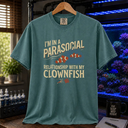 Saltwater aquarium graphic t-shirt featuring typography reading I'm In A Parasocial Relationship With My Clownfish framing an illustration of two clownfish in an anemone on a green shirt