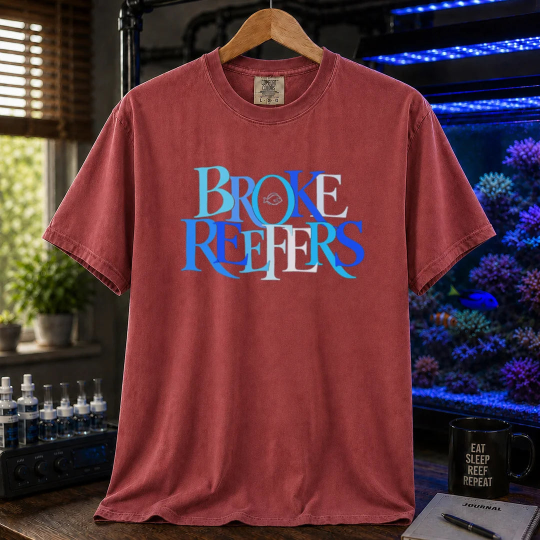 Saltwater aquarium graphic t-shirt featuring overlapping blue and white serif typography spelling Broke Reefers with a small fish outline on a maroon, red shirt