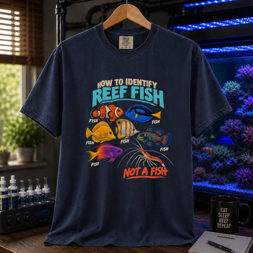 Saltwater aquarium graphic t-shirt featuring typography reading How To Identify Reef Fish above multiple fish labeled Fish and a cleaner shrimp labeled Not A Fish on a navy shirt