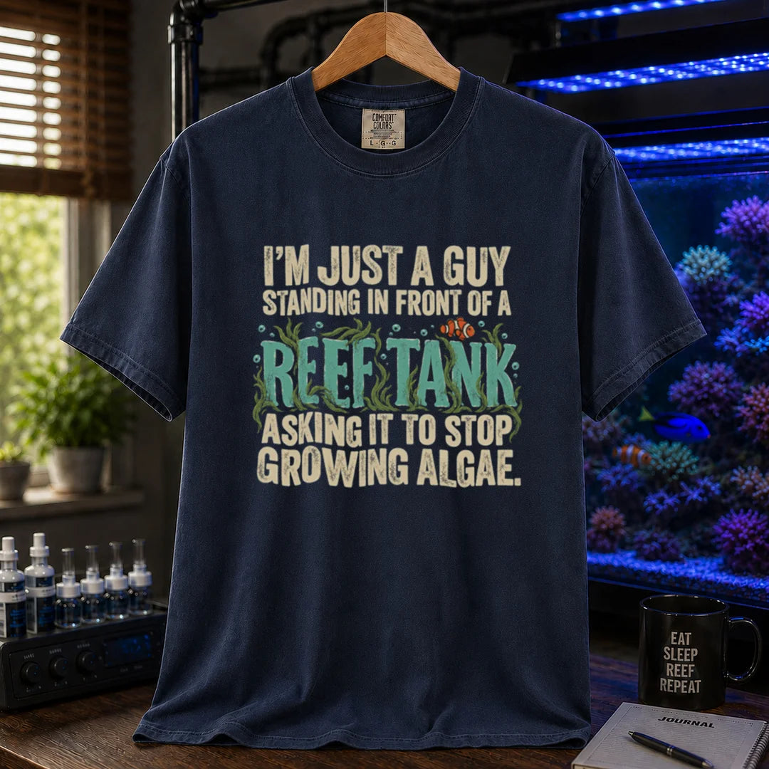 Saltwater aquarium graphic t-shirt featuring typography reading I'm Just A Guy Standing In Front Of A Reef Tank Asking It To Stop Growing Algae with algae and a clownfish on a navy shirt