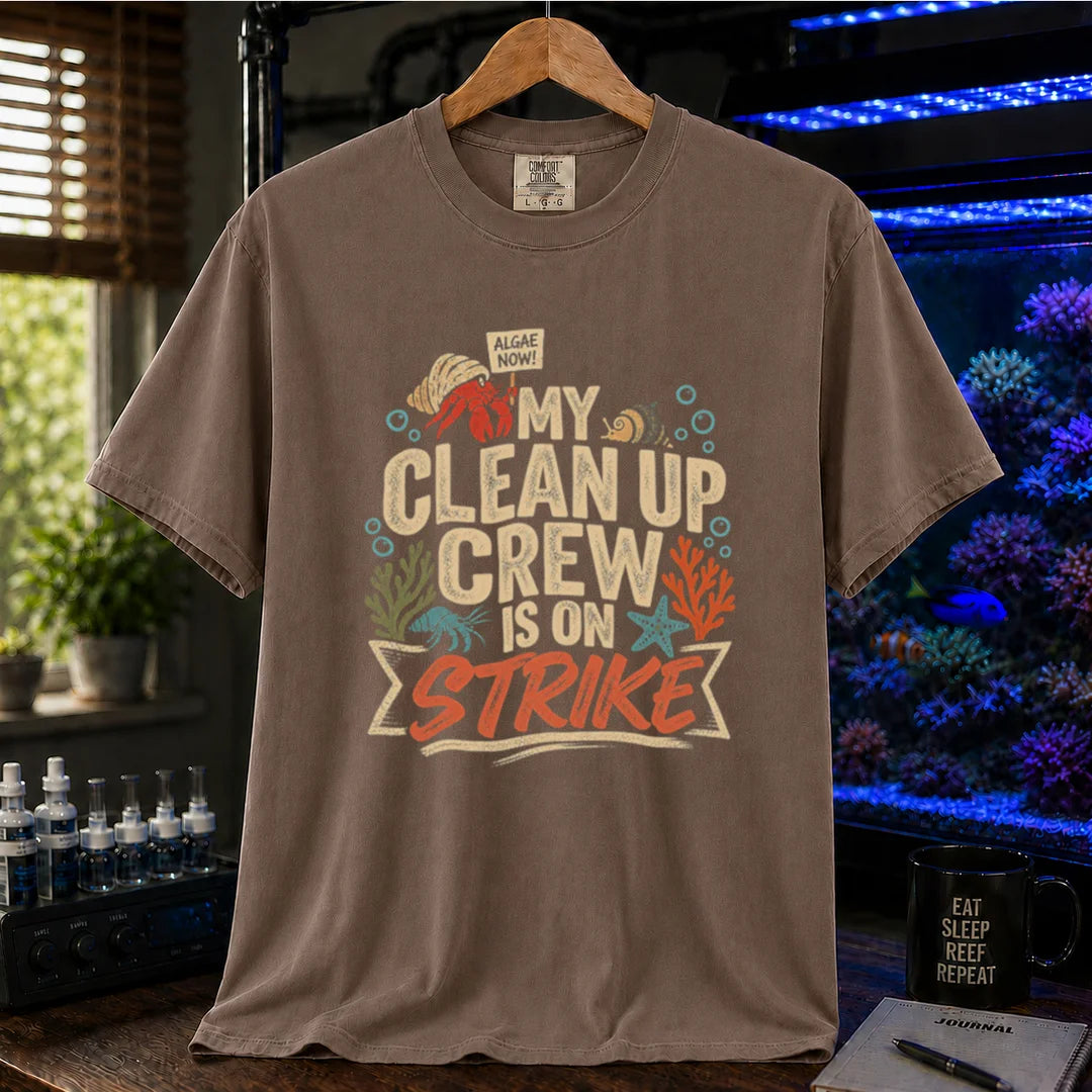 Saltwater aquarium graphic t-shirt featuring distressed typography reading My Clean Up Crew Is On Strike with illustrations of a hermit crab holding a protest sign and other marine cleanup animals on a brown T-Shirt