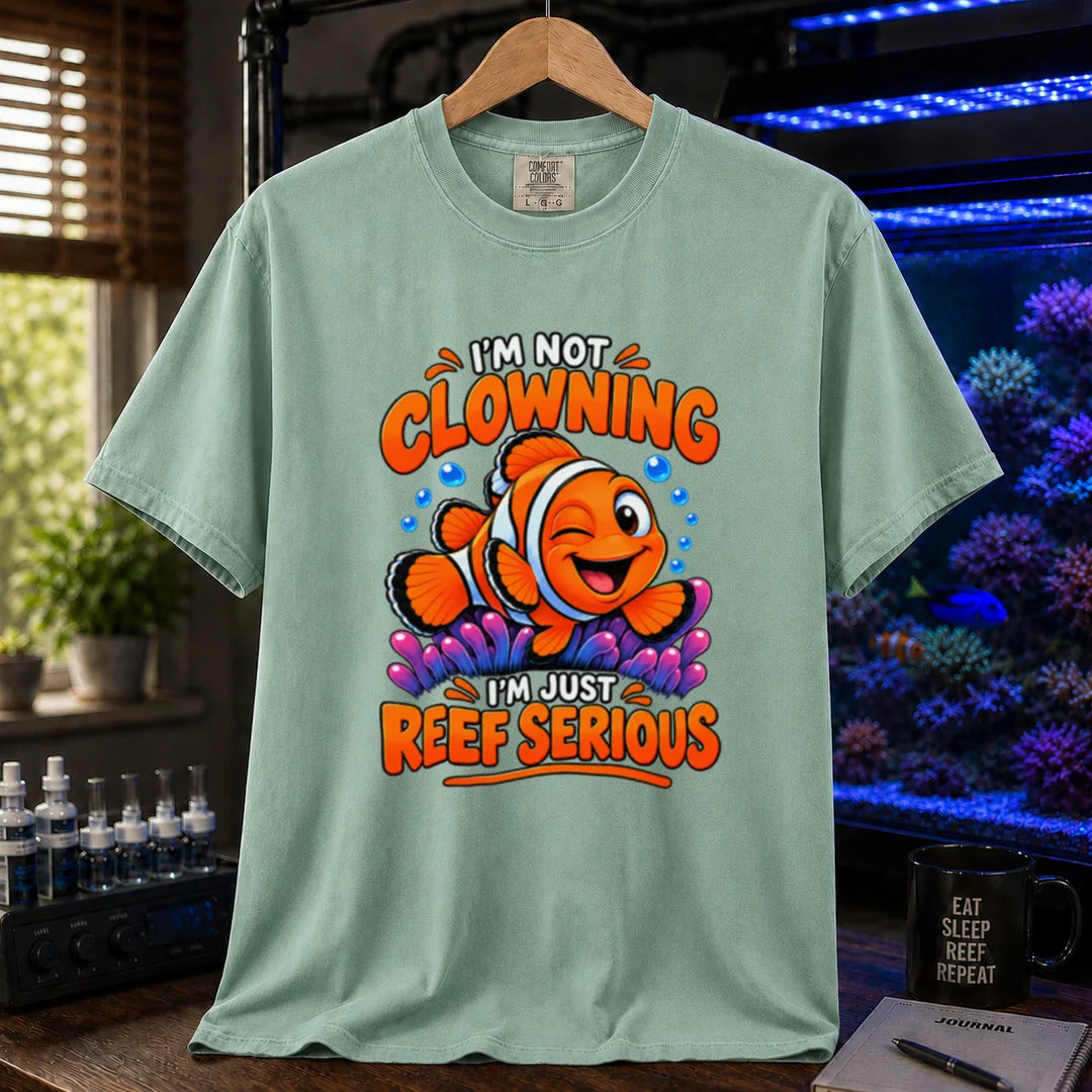 Saltwater aquarium graphic t-shirt featuring bold typography reading I'm Not Clowning I'm Just Reef Serious with a winking clownfish illustration on a light green T-Shirt