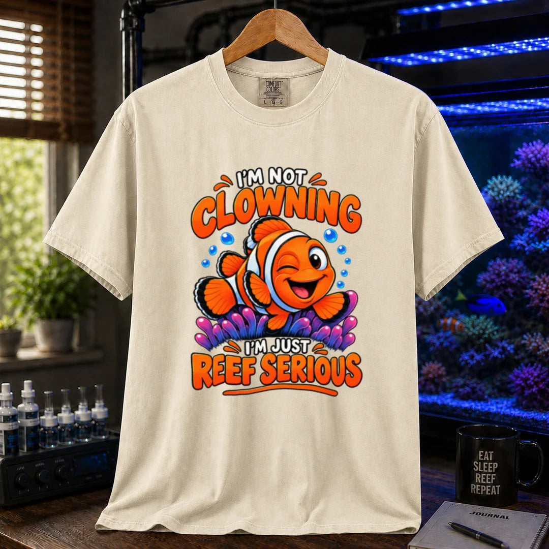 Saltwater aquarium graphic t-shirt featuring bold typography reading I'm Not Clowning I'm Just Reef Serious with a winking clownfish illustration on a beige, cream, ivory T-Shirt