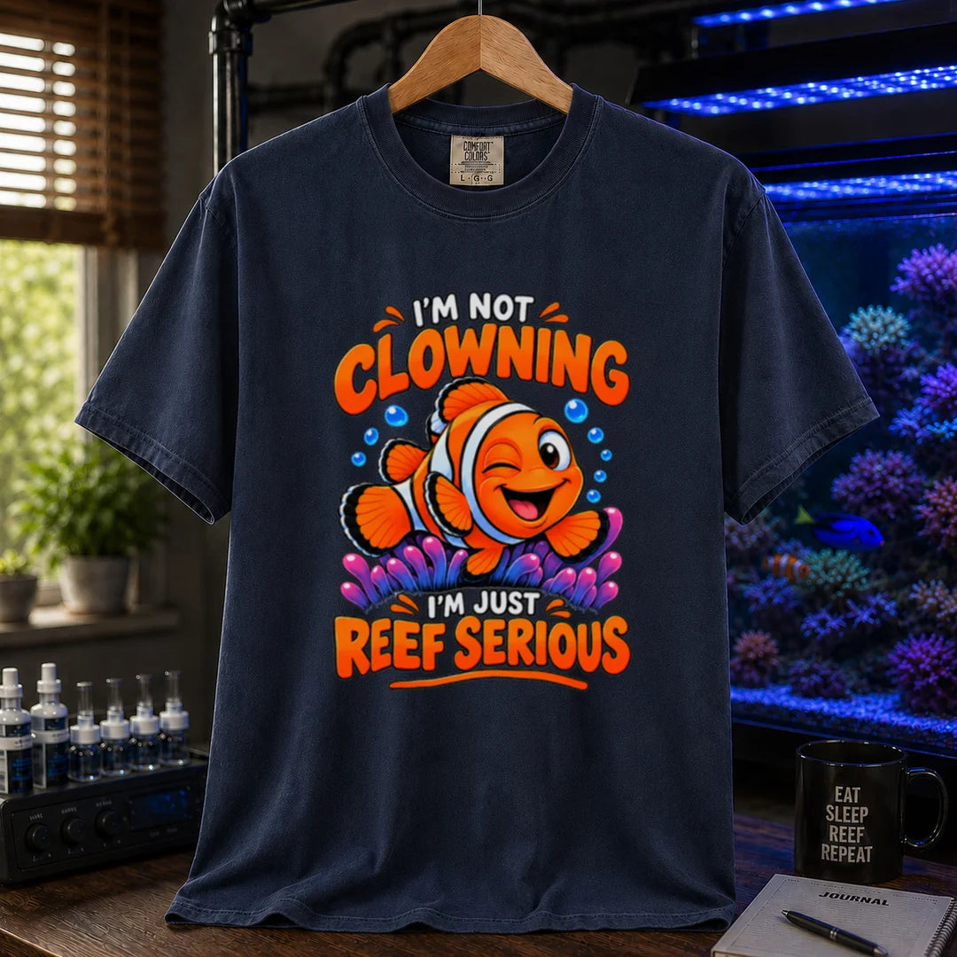 Saltwater aquarium graphic t-shirt featuring bold typography reading I'm Not Clowning I'm Just Reef Serious with a winking clownfish illustration on a navy T-Shirt