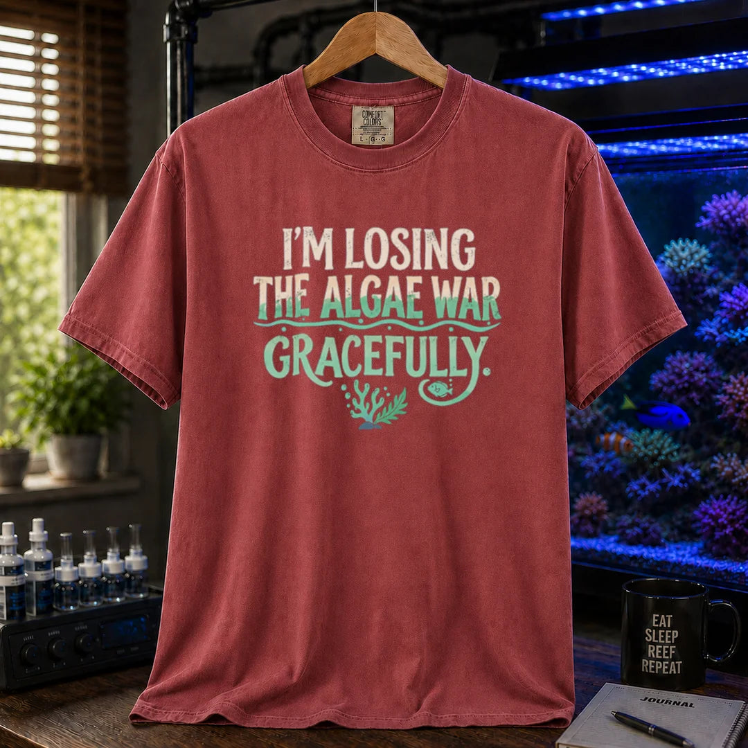 Saltwater aquarium graphic t-shirt featuring distressed typography reading I'm Losing The Algae War Gracefully with coral and fish illustrations on a maroon, red T-Shirt