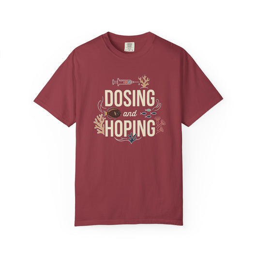 Broke Reefers graphic t-shirt featuring an illustration of a syringe and reef life with the text: DOSING AND HOPING, maroon crew neck tee