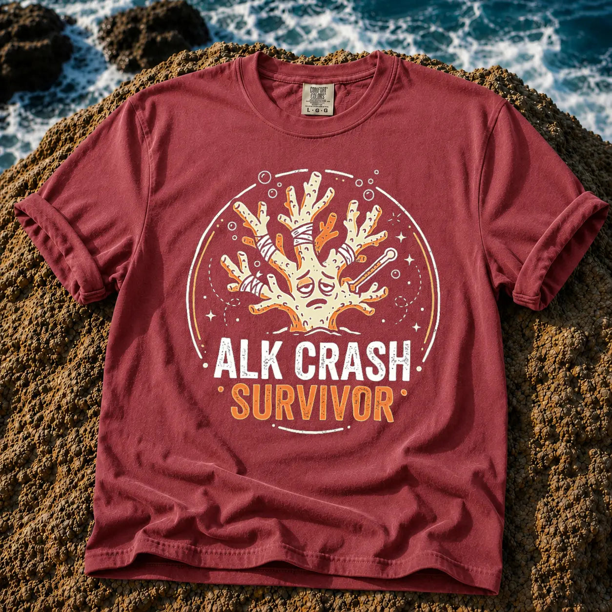 Broke Reefers saltwater aquarium graphic t-shirt featuring an expressive, bandaged coral illustration with the text: ALK CRASH SURVIVOR, maroon crew neck tee
